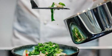 Шеф-кухар, що викладає страву на тарілку з каструлі Infinite Chef