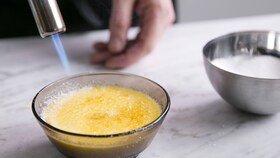 Кондитер, який карамелізує цукор на верхівці крем-брюле за допомогою кулінарного пальника