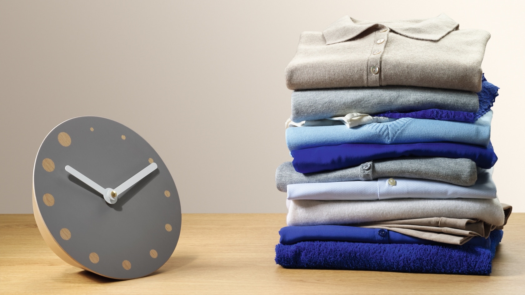 A clock next to a pile of shirts